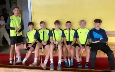 Chłopcy ubrani w stroje sportowe siedzą na ławce i pozują do zdjecia