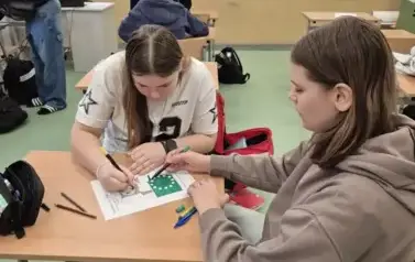 Uczennice klasy si&oacute;dmej siedzą przy ławce w sali matematycznej
