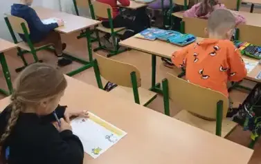Uczniowie klasy trzeciej w ławkach szkolnych
