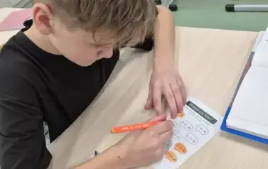 Chłopiec rozwiązuje łamigł&oacute;wkę matematyczną