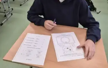 Chłopiec w czarnej bluzie przygląda się zadaniom matematycznym na kartkach