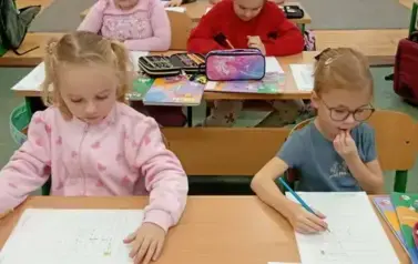 Dziewczynki z klasy pierwszej w ławkach szkolnych