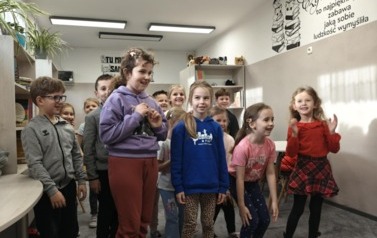 Grupa uczni&oacute;w klasy pierwszej bierze udział w zabawie ruchowej w bibliotece szkolnej