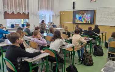 Uczniowie oglądają film edukacyjny wyświetlony na monitorze multimedialnym w sali lekcyjnej
