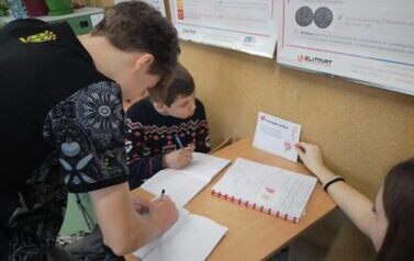 Uczniowie siedzą w ławce i wykonują zadania z karty pracy