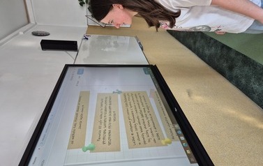 Uczennica czyta informacje o liczbie pi na tablicy multimedialnej