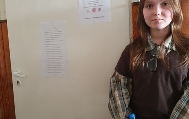 Uczennica stoi przy drzwiach sali szkolnej.jpeg