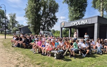 Dzieci ze szkołu na ławkach w amfiteatrze Topolina w Mielniku