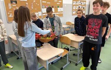 Dziewczynka częstuje cukierkami chłopc&oacute;w z klasy si&oacute;dmej.