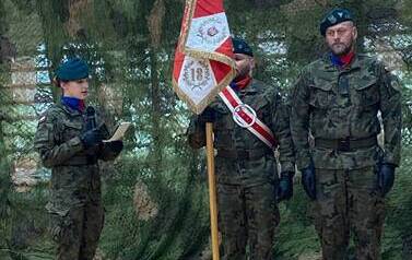 Dw&oacute;ch żołnierzy i żołnierka prezentują sztandar