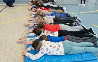 Grupa uczni&oacute;w leży na niebieskich materacach obok siebie
