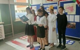 Grupa uczni&oacute;w stojąca przed publicznością. Dwie osoby w strojach galowych, pozostałe w strojach podobnych do stroj&oacute;w średniowiecznych.