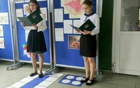 Dwie dziewczynki w strojach galowych, trzymające teczki.