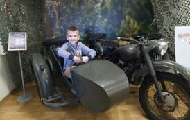 Chłopiec pozuje do zdjęcia w zabytkowym motocyklu.