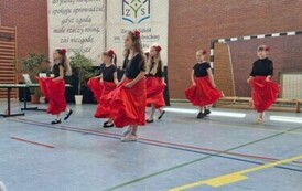 Dziewczynki w czarnych bluzkach i czerwonych sp&oacute;dniczkach.