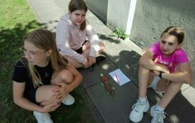 Trzy dziewczynki siedzące na chodniku.