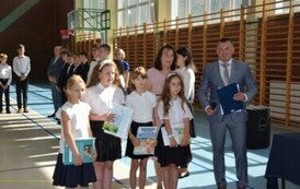 Uczennice klasy drugiej, kt&oacute;re otrzymały świadectwa za najlepsze wyniki w nauce pozują do zdjęcia podczas uroczystego zakończenia roku szkolnego wraz z dyrektorem plac&oacute;wki i wychowawcą.
