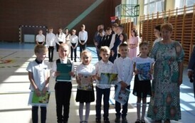 Uczniowie klasy pierwszej, kt&oacute;rzy otrzymali świadectwa za najlepsze wyniki w nauce pozują do zdjęcia podczas uroczystego zakończenia roku szkolnego wraz z  wychowawcą.