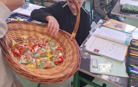 Chłopcy z klasy czwartej otrzymują cukierki z okazji Dnia Chłopaka.