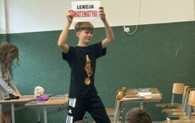 Uczeń trzyma kartkę z napisem - lekcja matematyki.