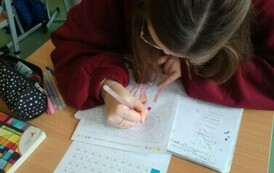 Uczennica pisząca w zeszycie z matematyki.