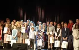 Grupa dzieci stojąca na scenie z prezentami.