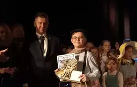 Mężczyzna i chłopiec z dyplomem i statuetka.