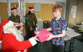 Mikołaj wręcza prezent uczniowi klasy &oacute;smej.
