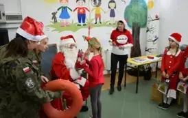 Mikołaj wręcza prezent uczennicy z klasy trzeciej.