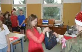 Mikołaj wręcza prezent uczennicy z klasy piątej.