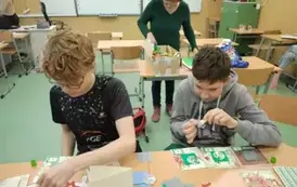 Dw&oacute;ch chłopc&oacute;w ozdabia kartki na Boże Narodzenie.