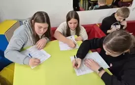 Uczennice siedzą przy stoliku i rozwiązują test