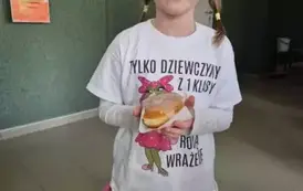 Dziewczynka w białej bluzce, r&oacute;żowej sp&oacute;dniczce, z pączkiem w dłoniach