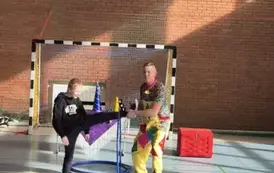 Chłopiec kręci hula hop nogą. Pomaga mężczyzna w kolorowym stroju