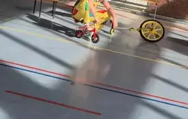 Mężczyzna w kolorowym stroju siedzi na bardzo małym rowerze