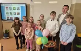 Dyrektor Zespołu Szk&oacute;ł w Mielniku, dw&oacute;ch chłopc&oacute;w z klasy czwartej oraz grupa dziewcząt z klasy drugiej podczas szkolnych obchod&oacute;w Dnia Kobiet.
