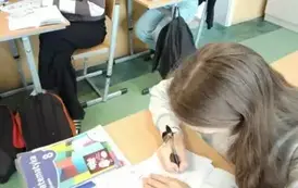 Uczennice siedzące w ławce wykonujące kodowanie