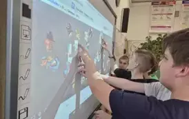 Chłopcy ukłądają puzzle na tablicy multimedialnej