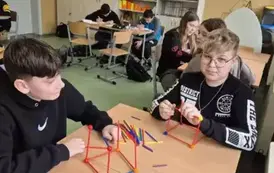 Sal matematyczna, uczniowie siedzą przy stolikach podzieleni na grupy. Na pierwszym planie dw&oacute;ch chłopc&oacute;w buduje liczbę Pi z kolorowych patyczk&oacute;w