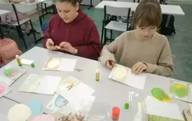 Dziewczynki siedzące przy stole wykonujące kartki wielkanocne.