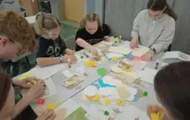 Uczniowie siedzący przy stole wykonujący kartki wielkanocne.