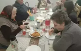 Uczennice z osobami z Domu Dziennego siedzące przy stole i spożywające gofry