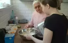 Uczennica z panią z domu Dziennego przygotowująca ciasto na gofry