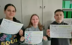 Uczniowie  stojący i prezentujący swoje prace