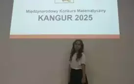 Uczennica w stroju galowym pozuje do zdjęcia
