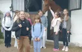 Grupa dzieczynek  z końmi w tle pozuje do zdjęcia