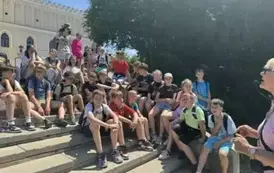 Grupa uczni&oacute;w siedzi na schodach i pozuje do zdjęcia