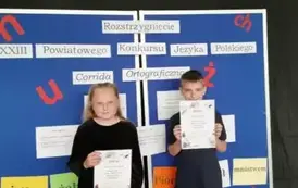 Zwycięzcy w konkursie pozują z dyplomamina tle niebieskiej tablicy