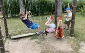 Czworo dzieci robi fikołki na linach i drabince na placu zabaw