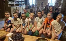 Dzieci siedzą w rzędzie na ławeczce i słuchają